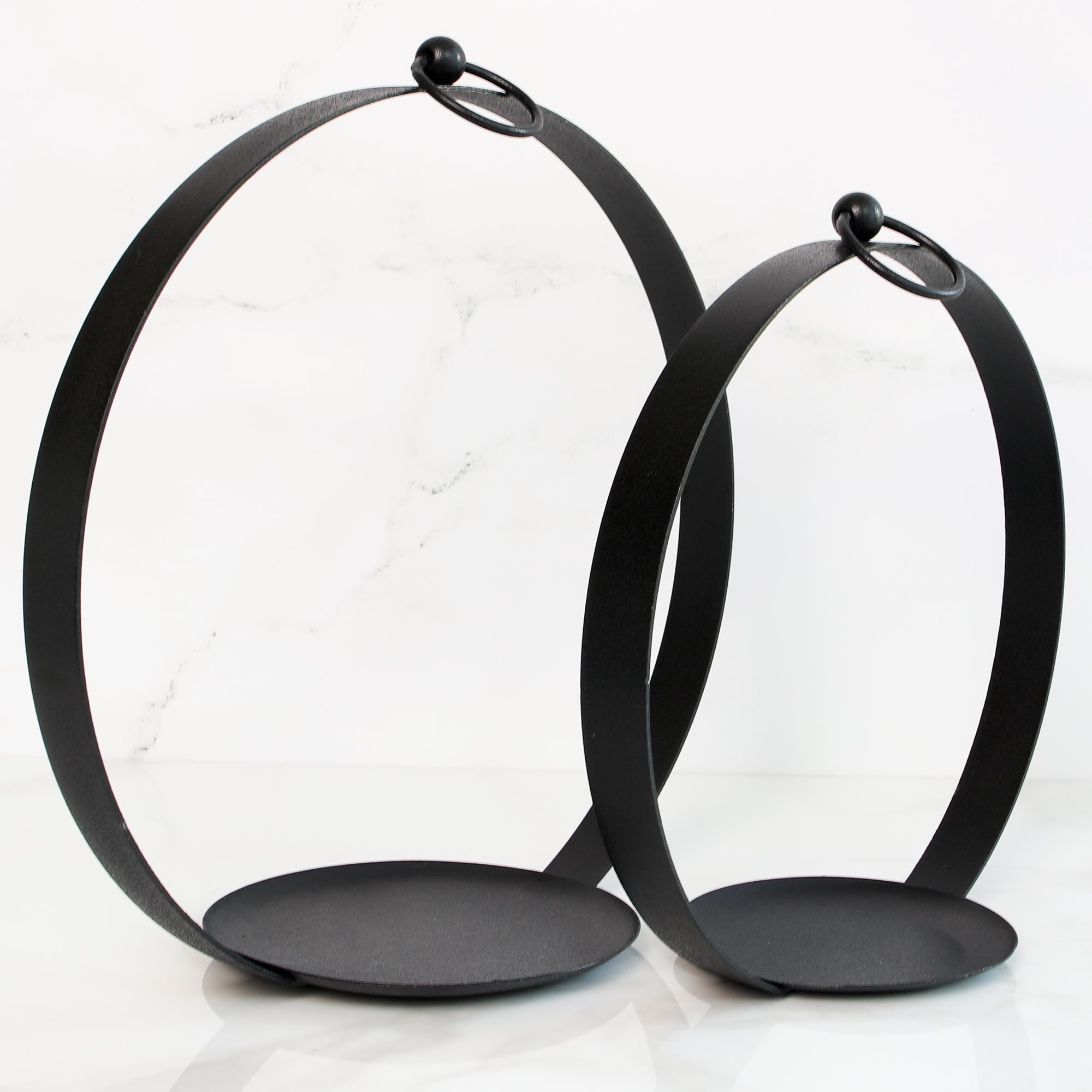 Round Black Metal Open Lantern Set of 2 displayed with pillar candles, enhancing the warm glow in a cozy setting.