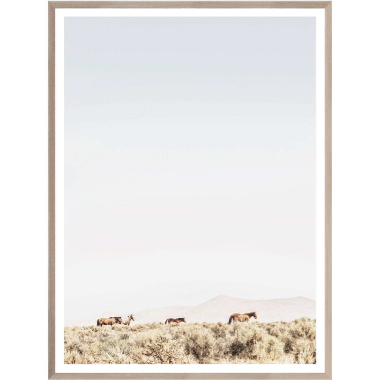 Wild Mountain Horses art piece featuring a group of horses trekking across a soft-toned landscape under a clear sky, framed in a light wood frame. Ideal for animal lovers and nature enthusiasts.
