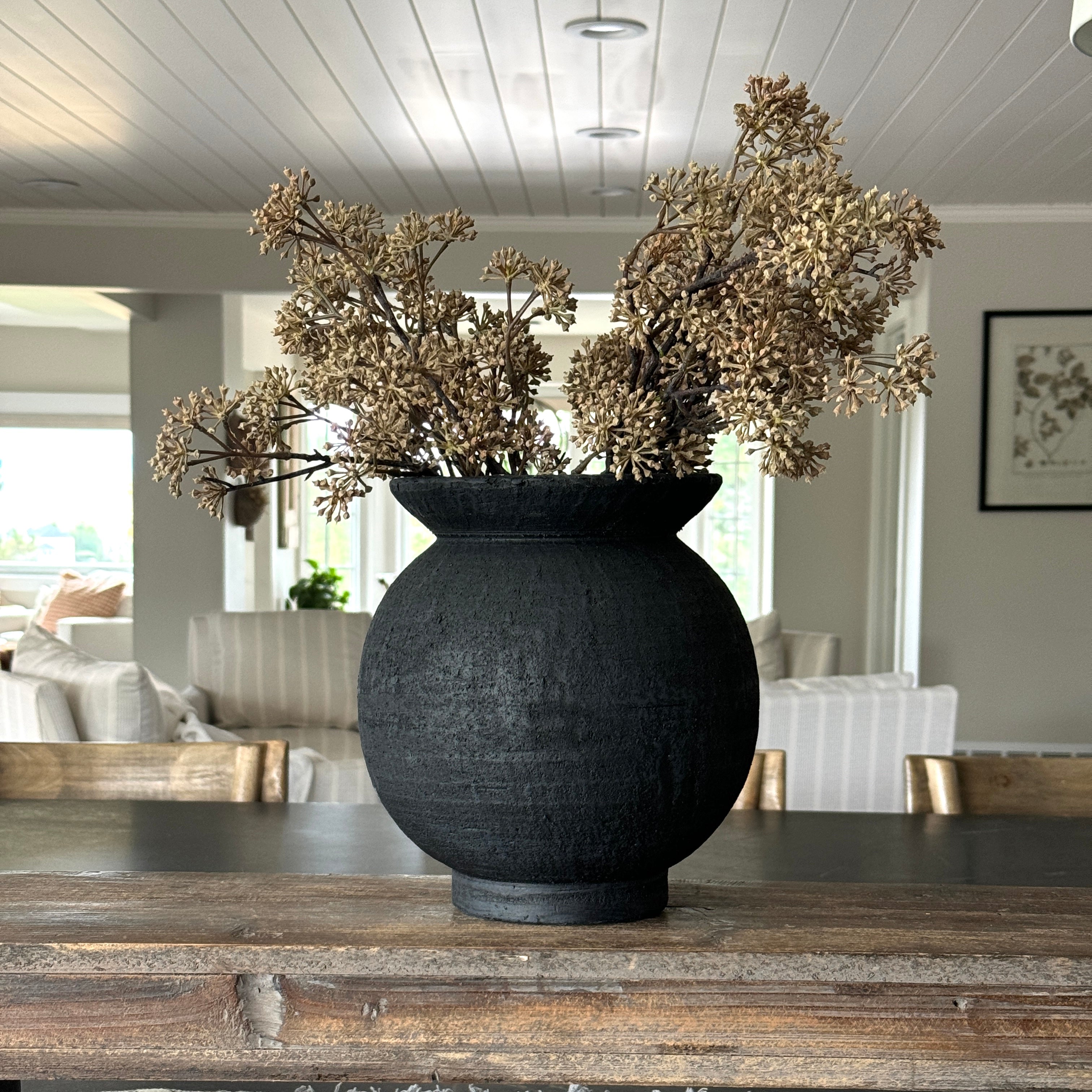 The versatile 9.5" Black Paul Vase displayed with decorative elements, showcasing its integration into modern interiors.