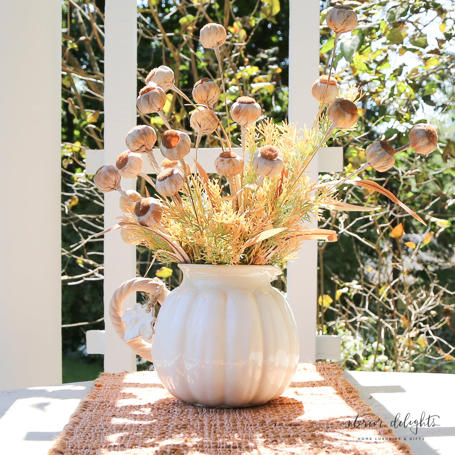 Ceramic white pumpkin pitcher showcased with decorative mixed green foliage, ideal for serving drinks.