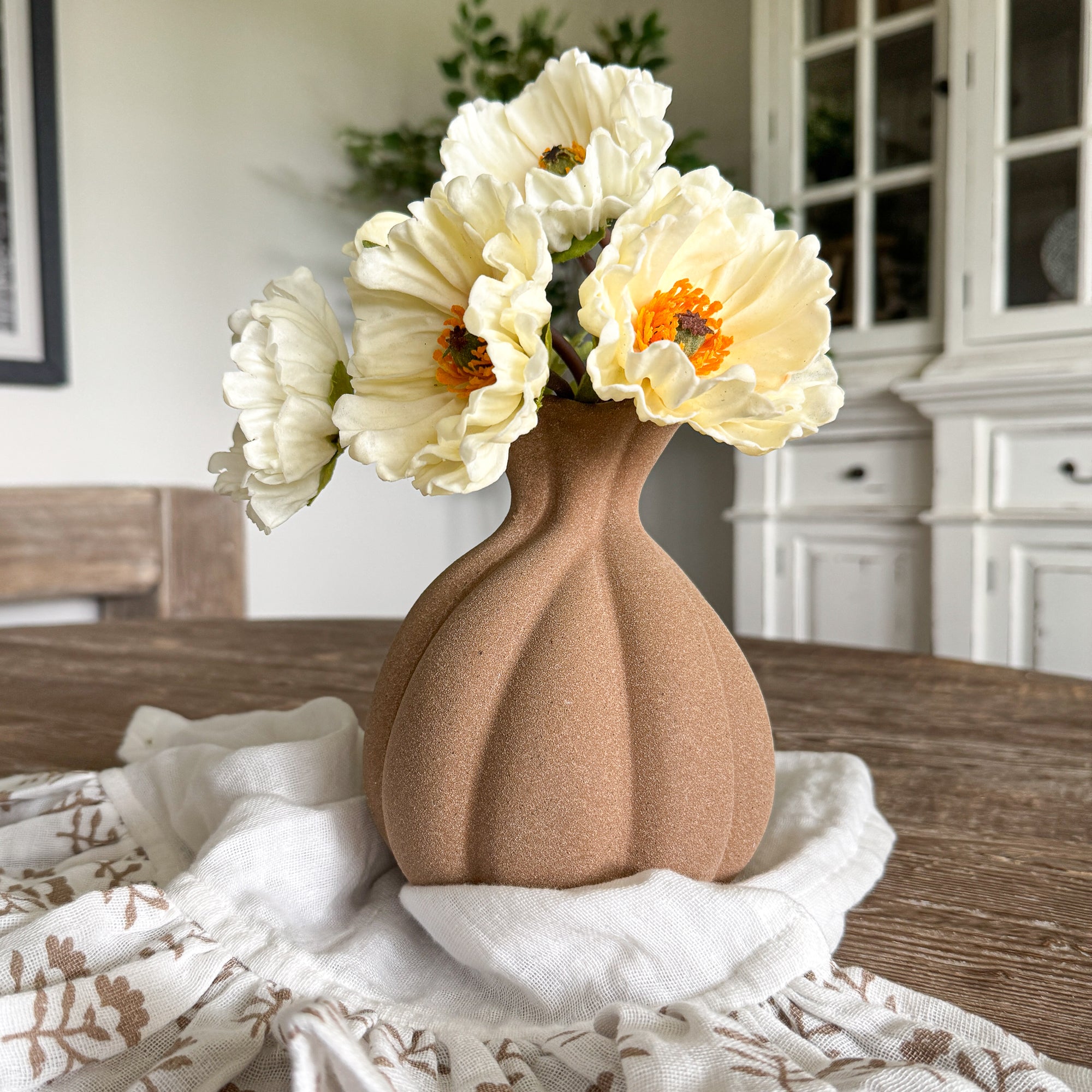 7” Brown Stoneware Vase showcasing rustic charm and elegance with its scalloped opening, curving pleats, and textured surface, perfect for displaying florals or as a standalone decor piece.