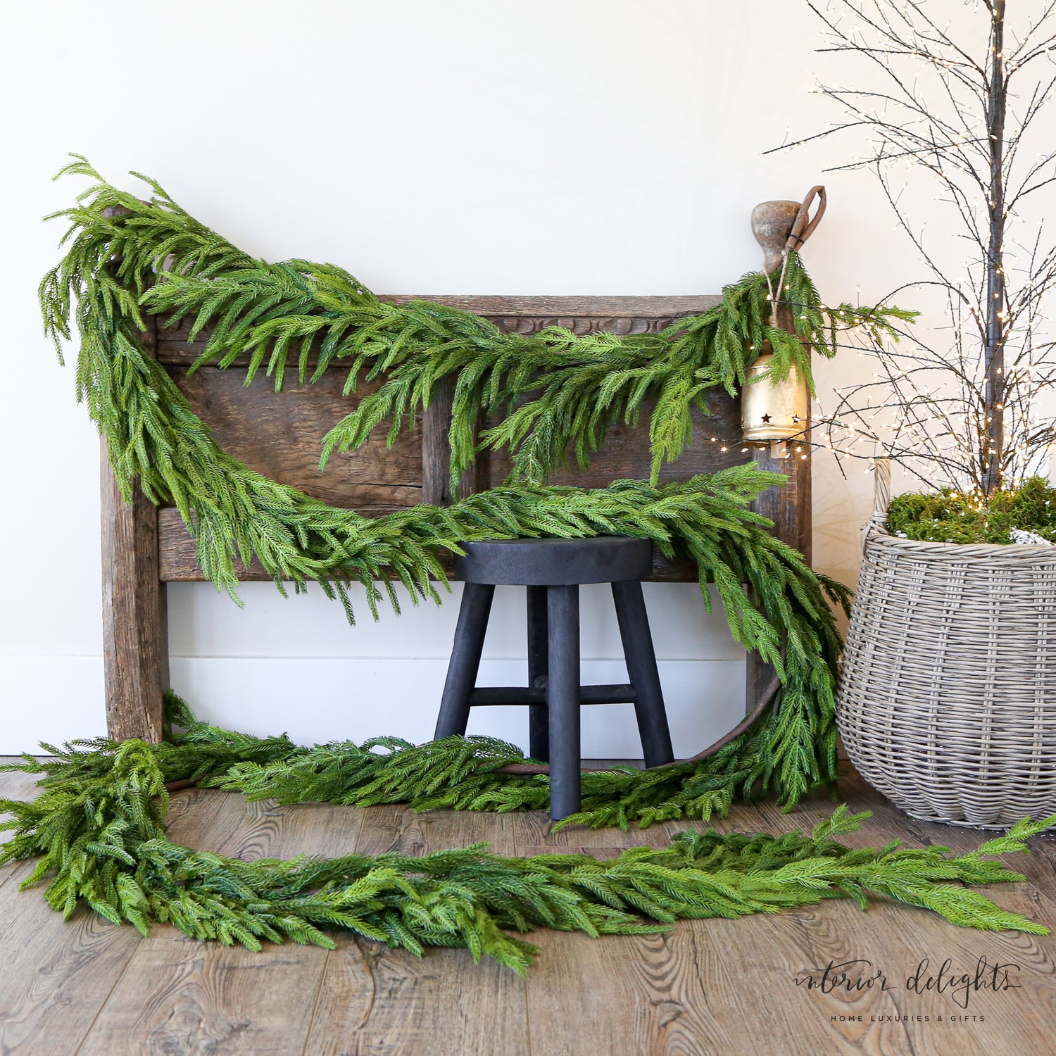 Festively decorated 15ft Real Touch Norfolk Pine Garland draped over a mantelpiece, embellished with ribbons and ornaments for a holiday touch.