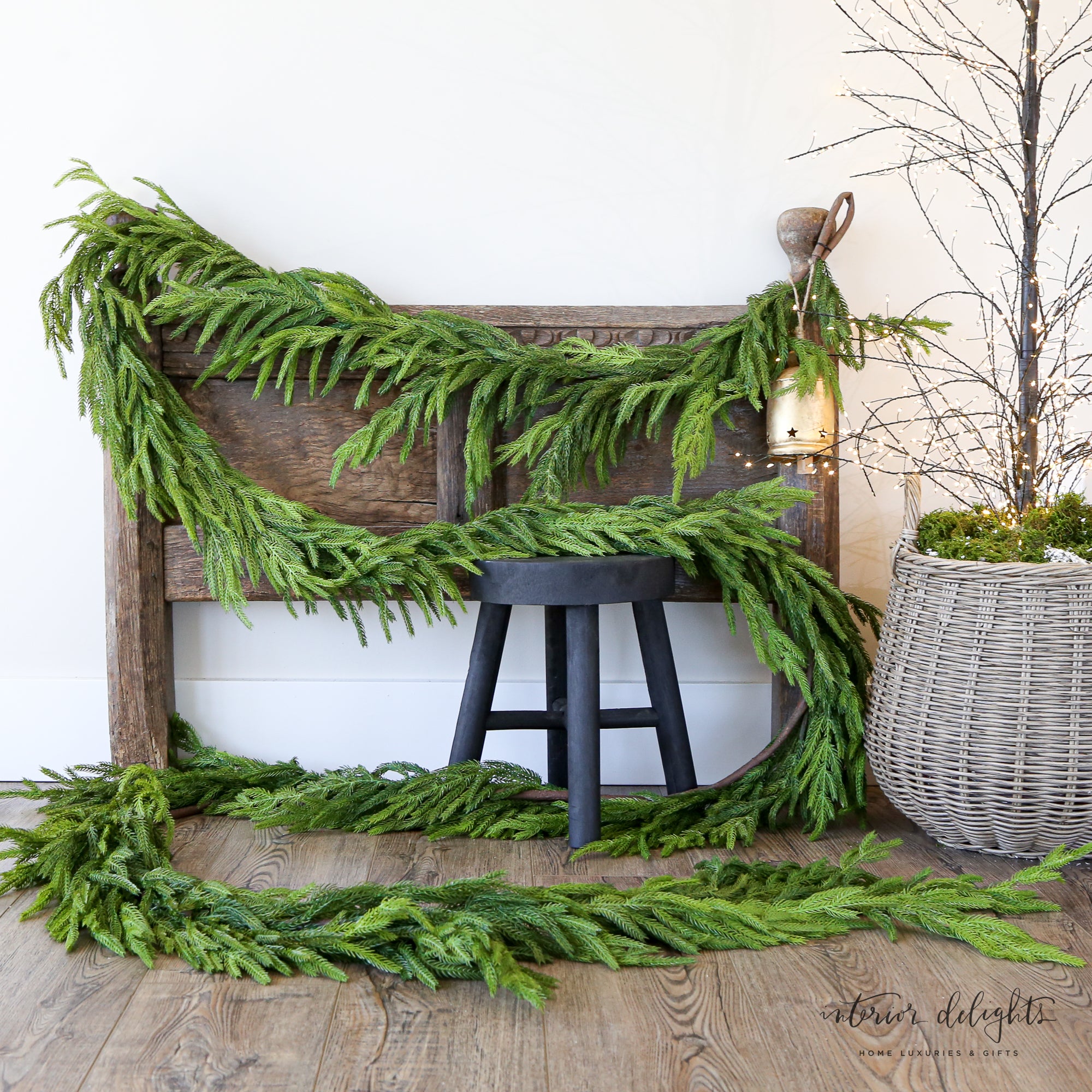 Festively decorated 15ft Real Touch Norfolk Pine Garland draped over a mantelpiece, embellished with ribbons and ornaments for a holiday touch.