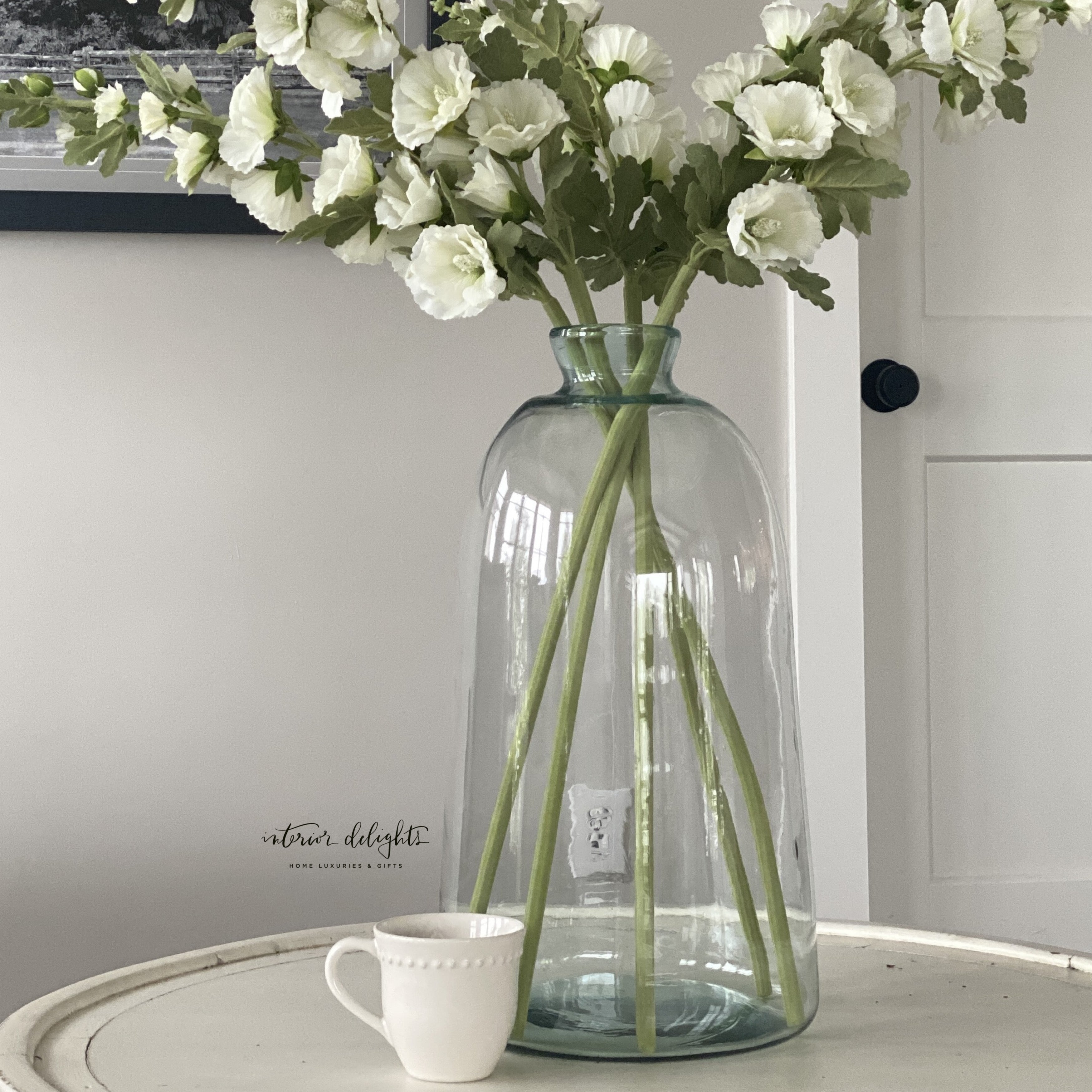 Elegant 43" White Hollyhock Stem showcased in a vase, highlighting its realistic floral details and soft white blossoms.