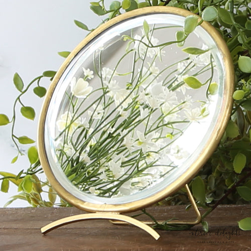 Round Antique Brass Mirror displayed on a vanity, showcasing its vintage charm and warm brass finish, perfect for adding elegance to any space.