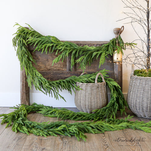 15ft Real Touch Norfolk Pine Garland displayed elegantly on a staircase railing, showcasing its realistic texture and lush greenery.