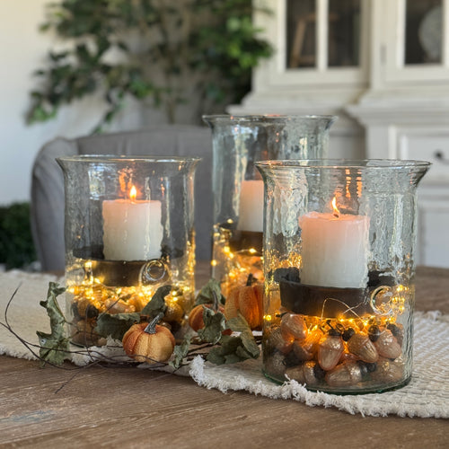 Medallion Hurricane Candle Holder in clear textured glass with dark metal insert, perfect for all-season decor.