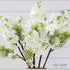 White Lilac Spray on a textured background, emphasizing its maintenance-free quality and elegance.